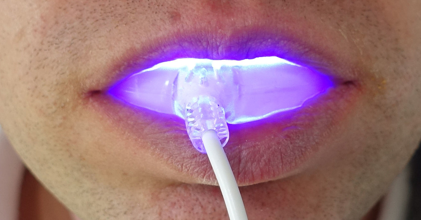 Person using at-home uv light teeth whitening device