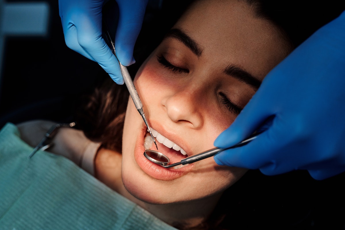 Dentist performing a check-up on a woman with healthy teeth and gums after using mouthwash with braces