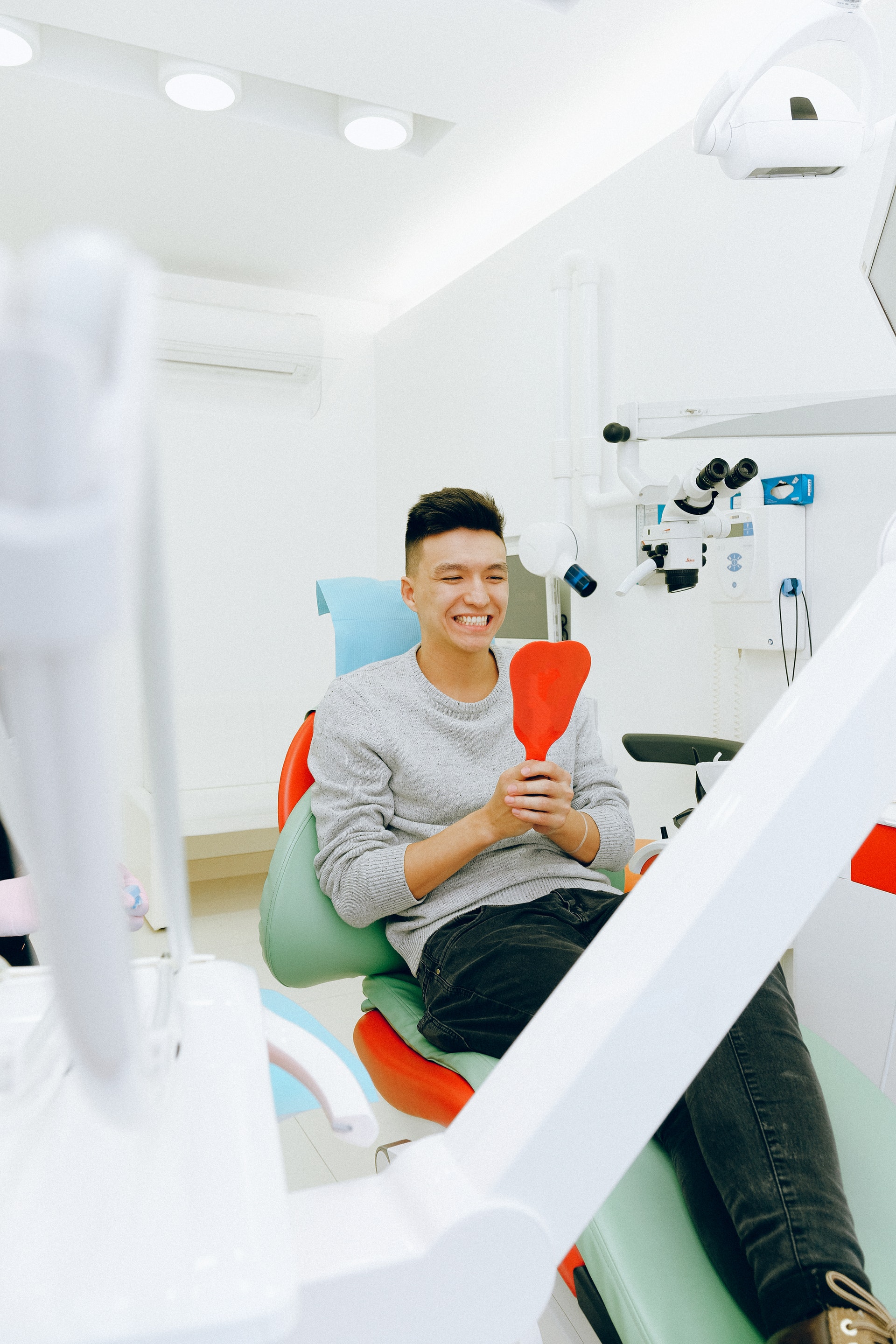 man sitting in dental chair looking at his whitened teeth