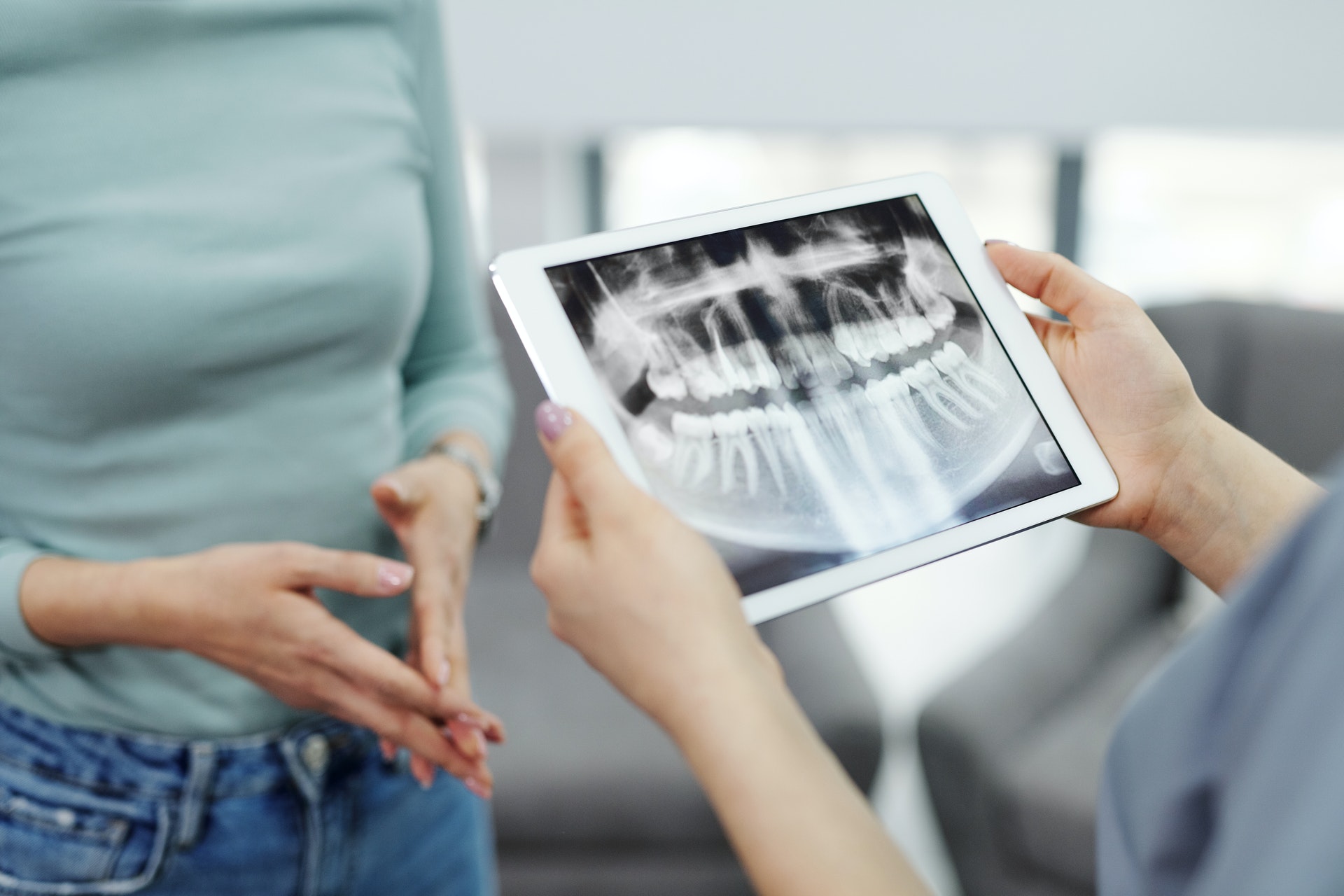 person holding iPad with an x-ray of a mouth with dental fillings