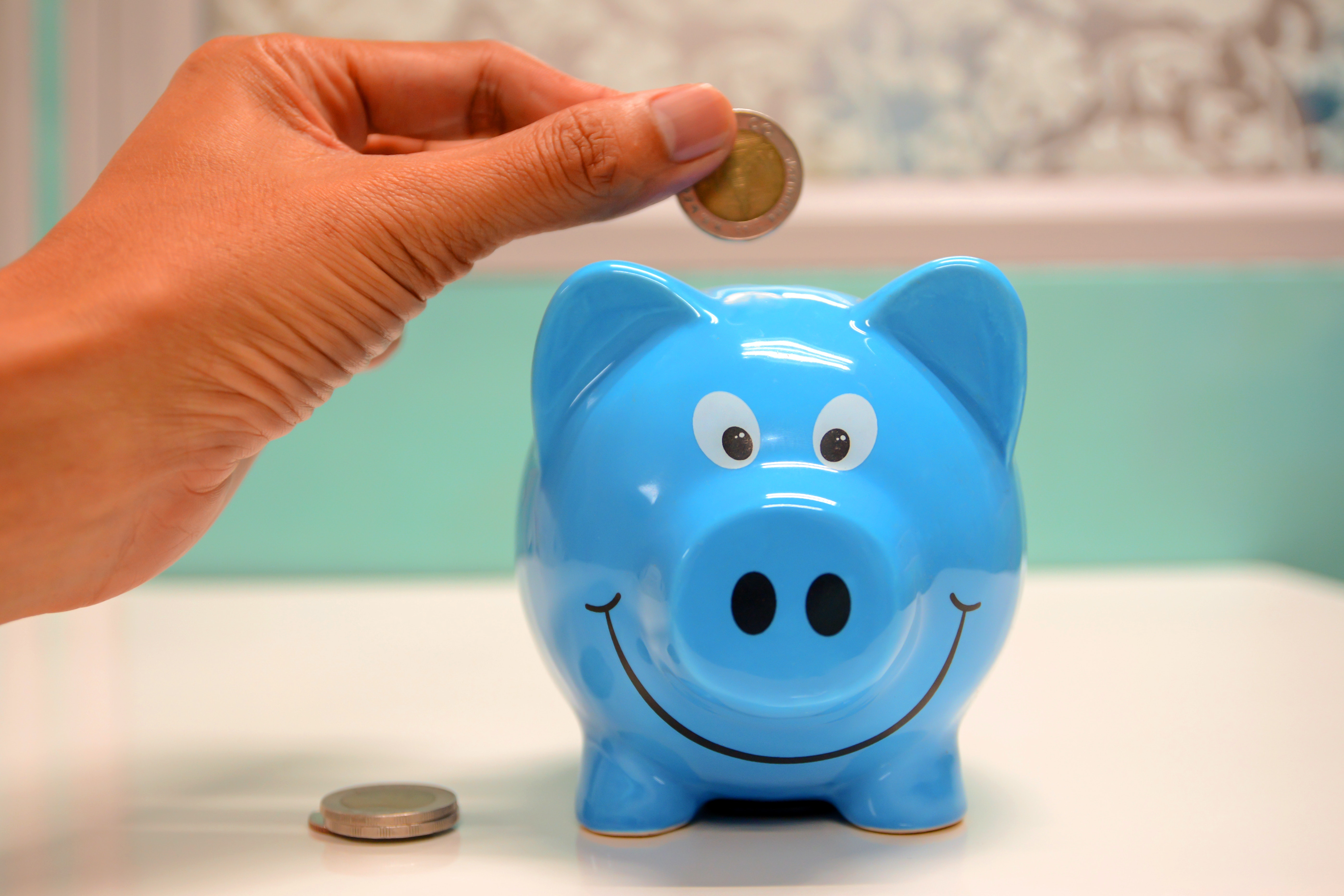 Man dropping coin into a piggy bank, representing low cost dental care for veterans