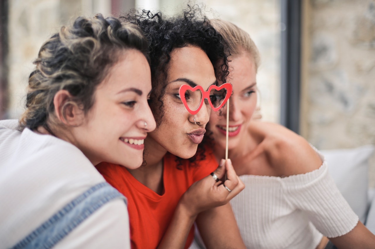 Three women looking through heart glasses