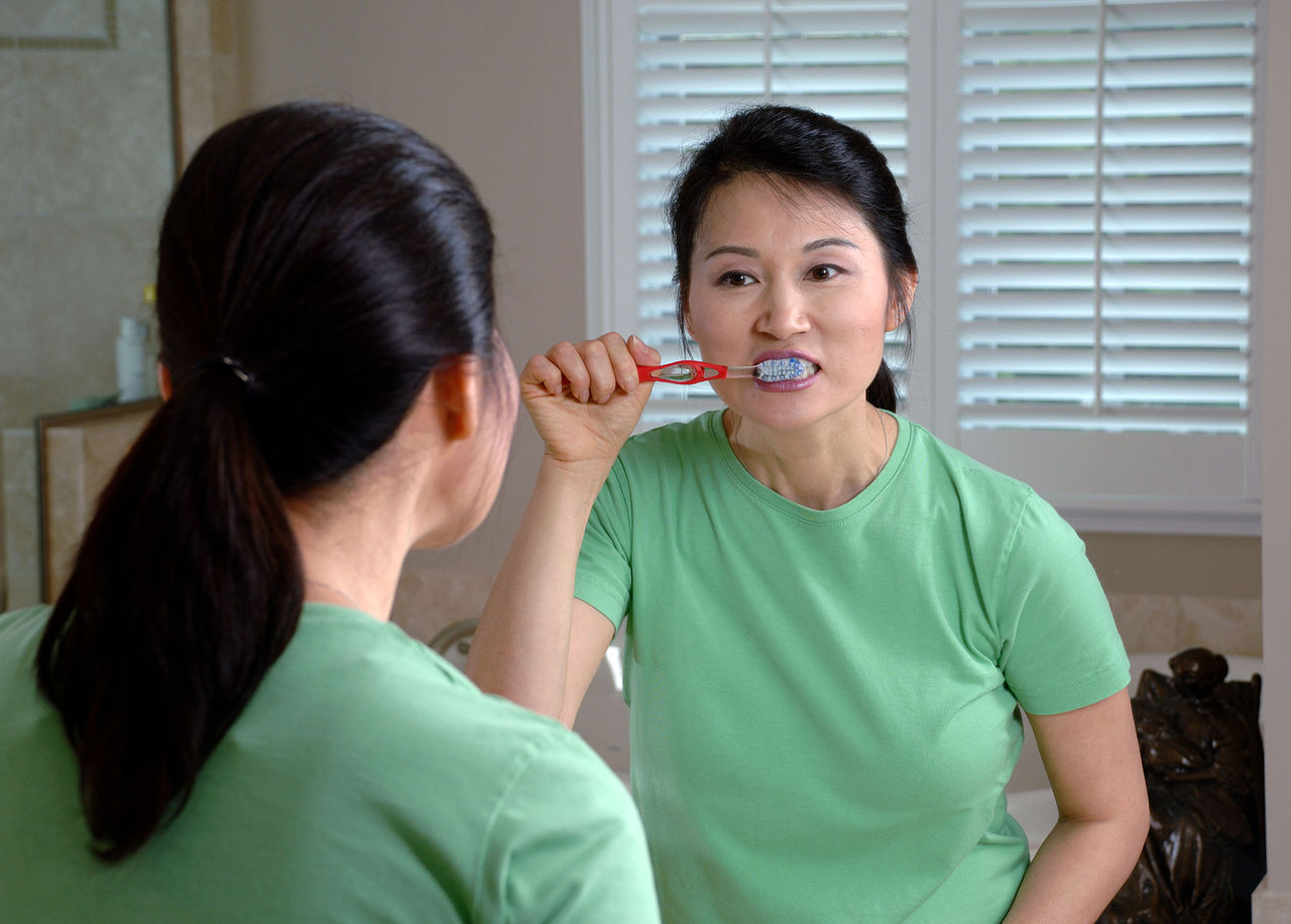 Woman brushing teeth to help prevent tooth abscesses